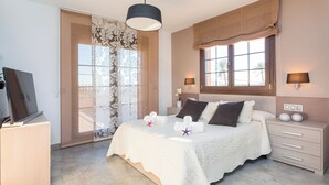 Une chambre à coucher avec un lit, des lampes de chevet, une télévision, un bureau et une fenêtre avec des rideaux.