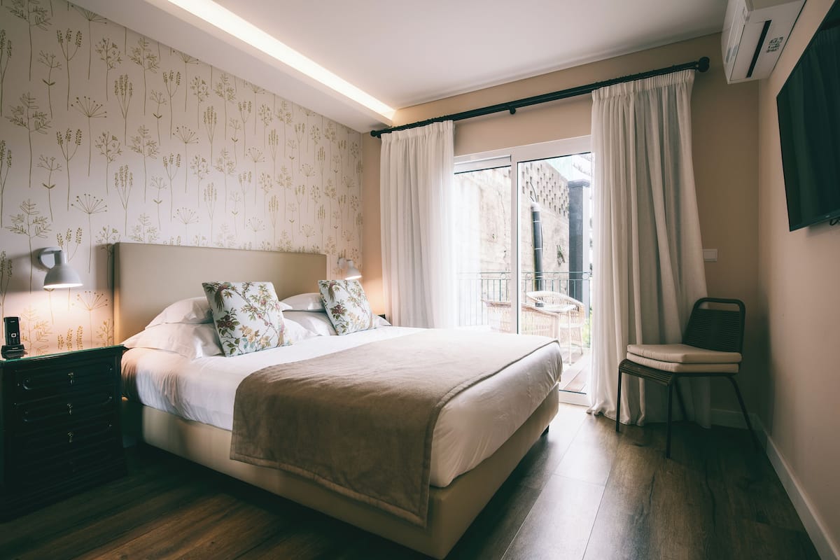 A bedroom with a bed, bedside table, lamp, and a view of the outside balcony.