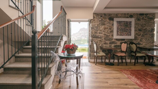 Amplia sala de estar con una escalera, una mesa de comedor con sillas y vistas al exterior.