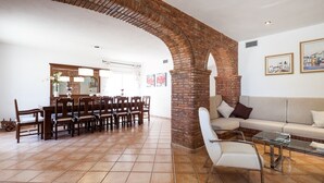 A spacious living area with a brick archway, a dining table with chairs, a sofa, and a glass coffee table. - Large Villa near Ibiza Town Sleeps 20/22 (Ibiza)