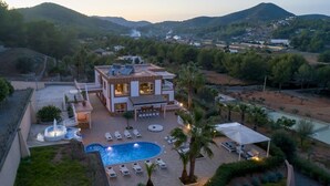 A large house with a swimming pool, outdoor seating, and a view of the surrounding landscape.