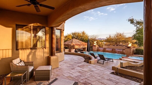 Un patio cubierto con mobiliario exterior, piscina y vistas del paisaje.