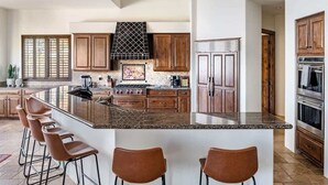 Una cocina con una isla grande, armarios de madera, electrodomésticos de acero inoxidable y una campana extractora negra.