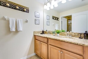 A bathroom with a granite countertop, wooden cabinets, a large mirror, and a vanity with a sink. - Ev7858ha - Paradise Palms Resort - 4 Bed 3 Baths Townhouse (Kissimmee)