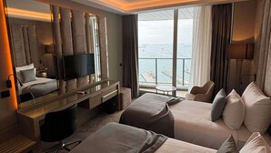A hotel room with two beds, a desk, a TV, and a large window with a view of the sea. - Best Western Premier Ottoperla Hotel (Istanbul)
