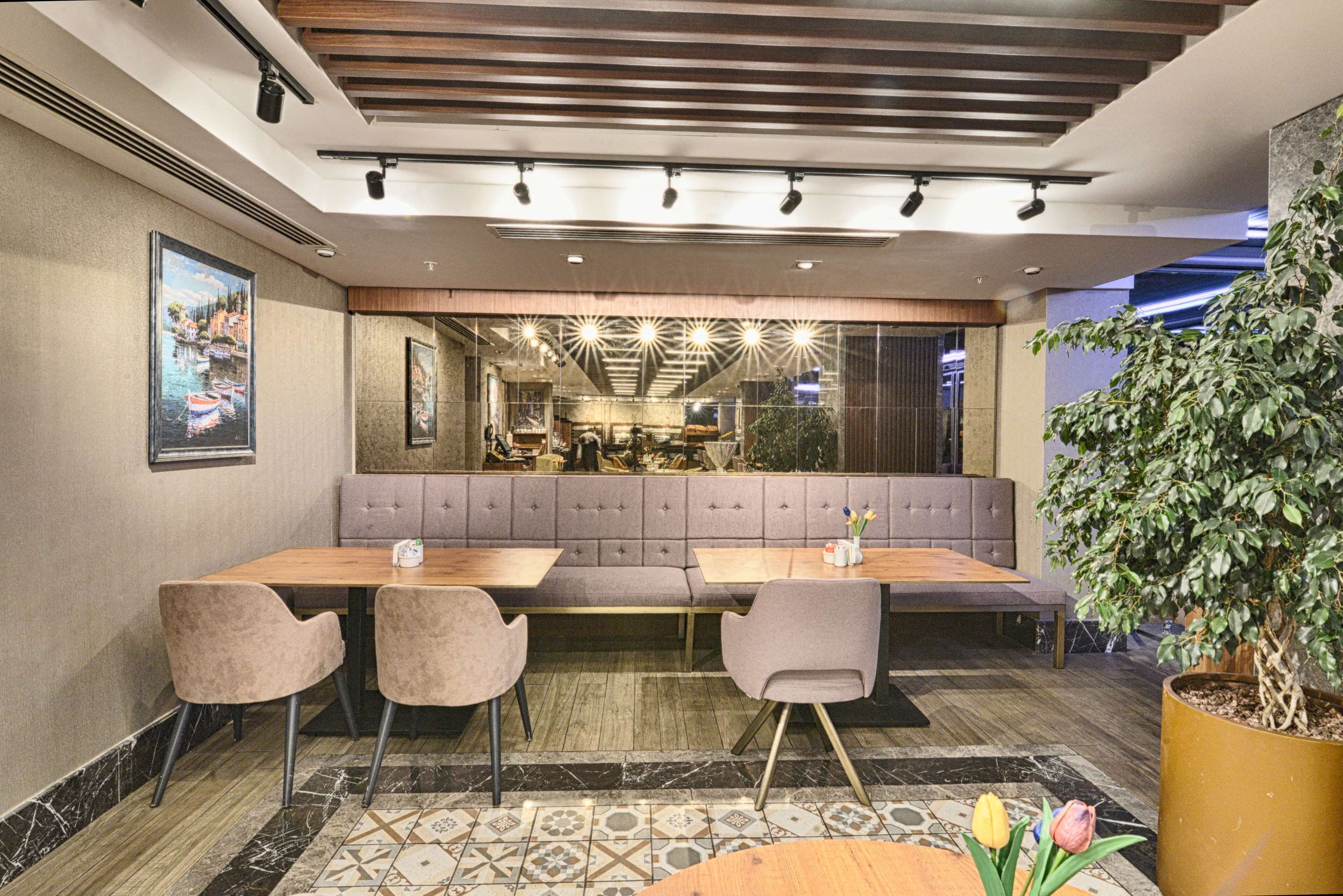 Uma sala de jantar moderna com uma mesa comprida, assentos acolchoados e um vaso de plantas.