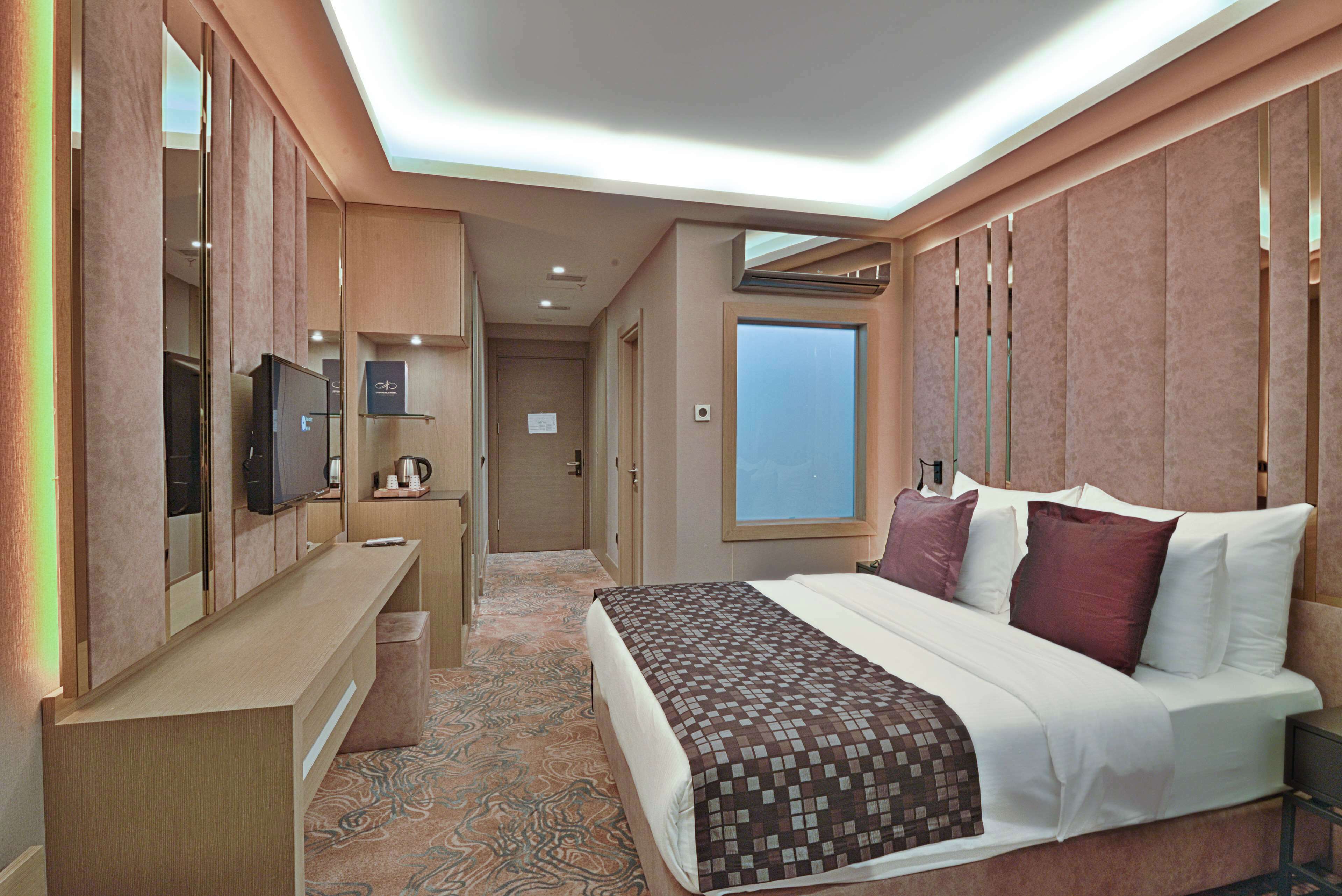 A hotel room with a bed, a desk, a television, and a window.
