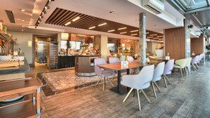 A modern hotel lobby with a central seating area, a kitchen visible through glass, and a high ceiling with skylights. - Best Western Premier Ottoperla Hotel (Istanbul)