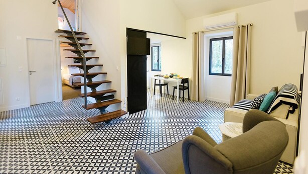 A spacious living area with a black and white patterned floor, a staircase, a dining area, and a sofa with patterned cushions. - Sintra Bliss A Part (Sintra)