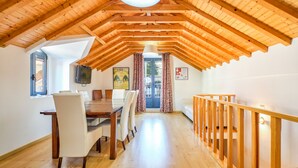 A dining area with a wooden ceiling, a dining table, chairs, and a television on the wall. - Sintra Bliss A Part (Sintra)