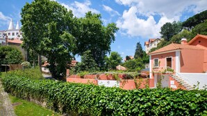 A residential area with a prominent tree, a pink building with a staircase, and a cobblestone path. - Sintra Bliss A Part (Sintra)