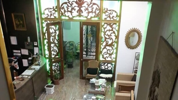 Una escalera conduce a una sala de estar con piso estampado, un mostrador de recepción y paneles decorativos.