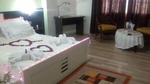 Una habitación de hotel con una cama bien hecha, una mesita con un florero, una silla y un sofá.