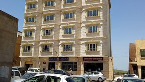 Un edificio de varios pisos con fachada simétrica, múltiples balcones y una entrada a nivel de calle con señalización.