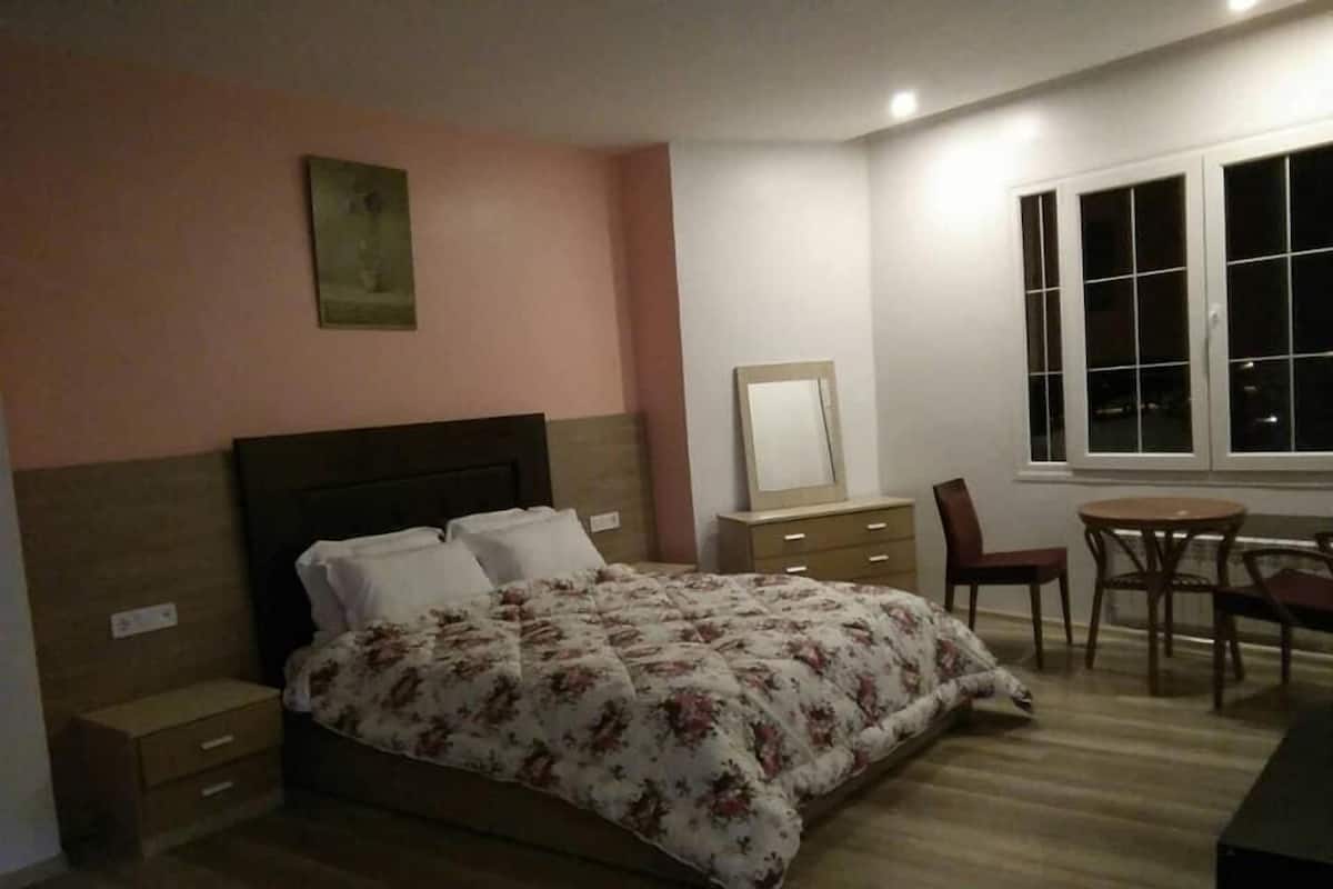 A bedroom with a bed, a dresser, a chair, and a table.