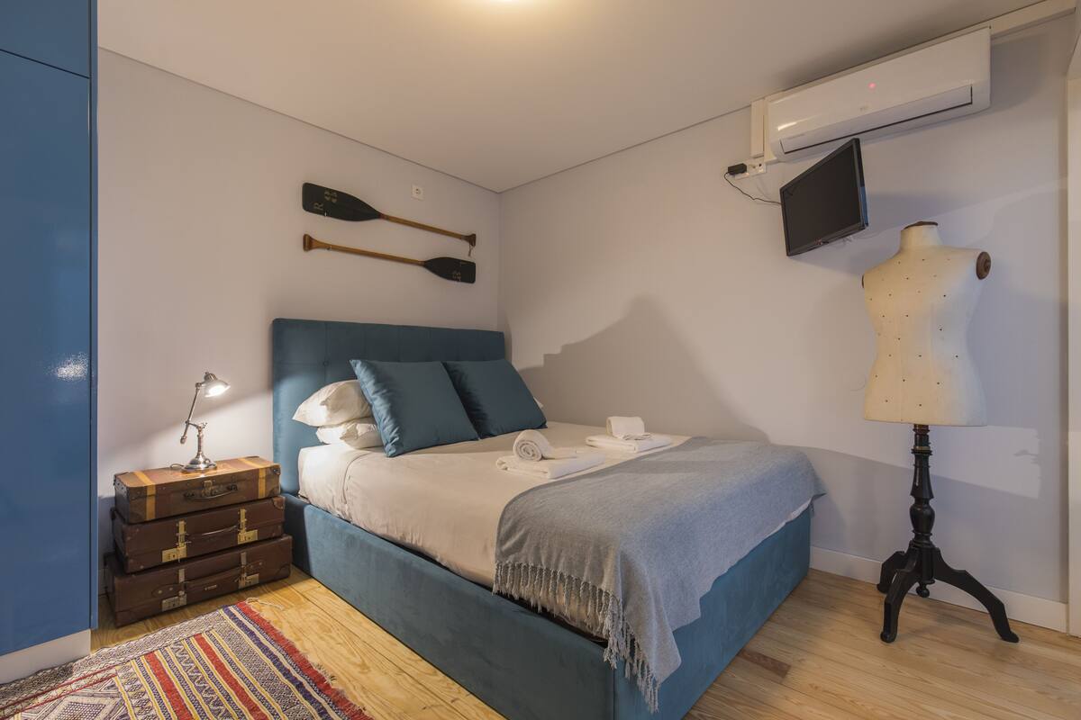 A bedroom with a bed, a dresser, a lamp, a mannequin, and wall-mounted items.