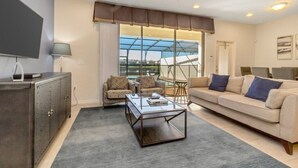 Una sala de estar moderna con sofá, sillones, una mesa de centro y televisión.