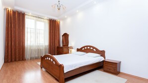 A bedroom with a wooden bed, nightstands, a lamp, and a window with curtains.