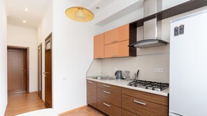A modern kitchen with wooden cabinets, a gas stove, and a white refrigerator.