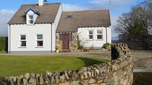 A two-story house with a stone foundation and a grey tiled roof. - Rathmullan Holiday Homes (Rathmullan)