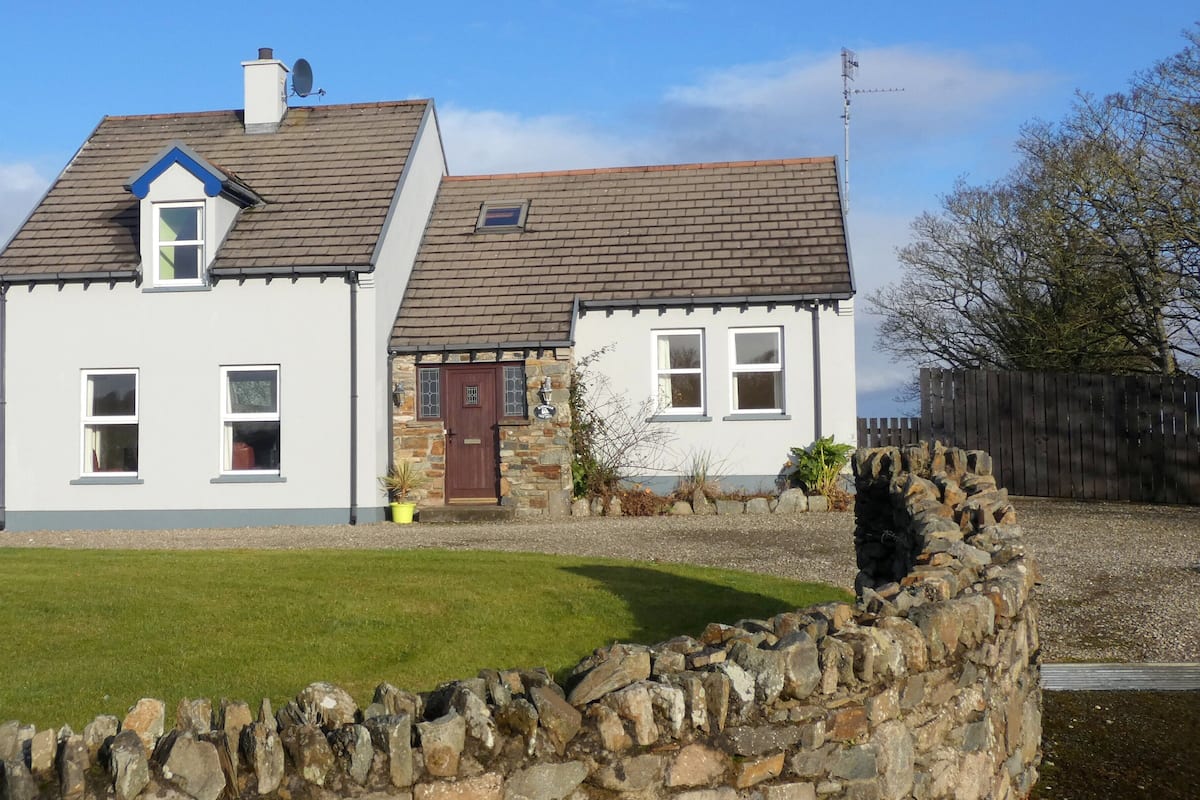 A two-story house with a stone foundation and a grey tiled roof.
