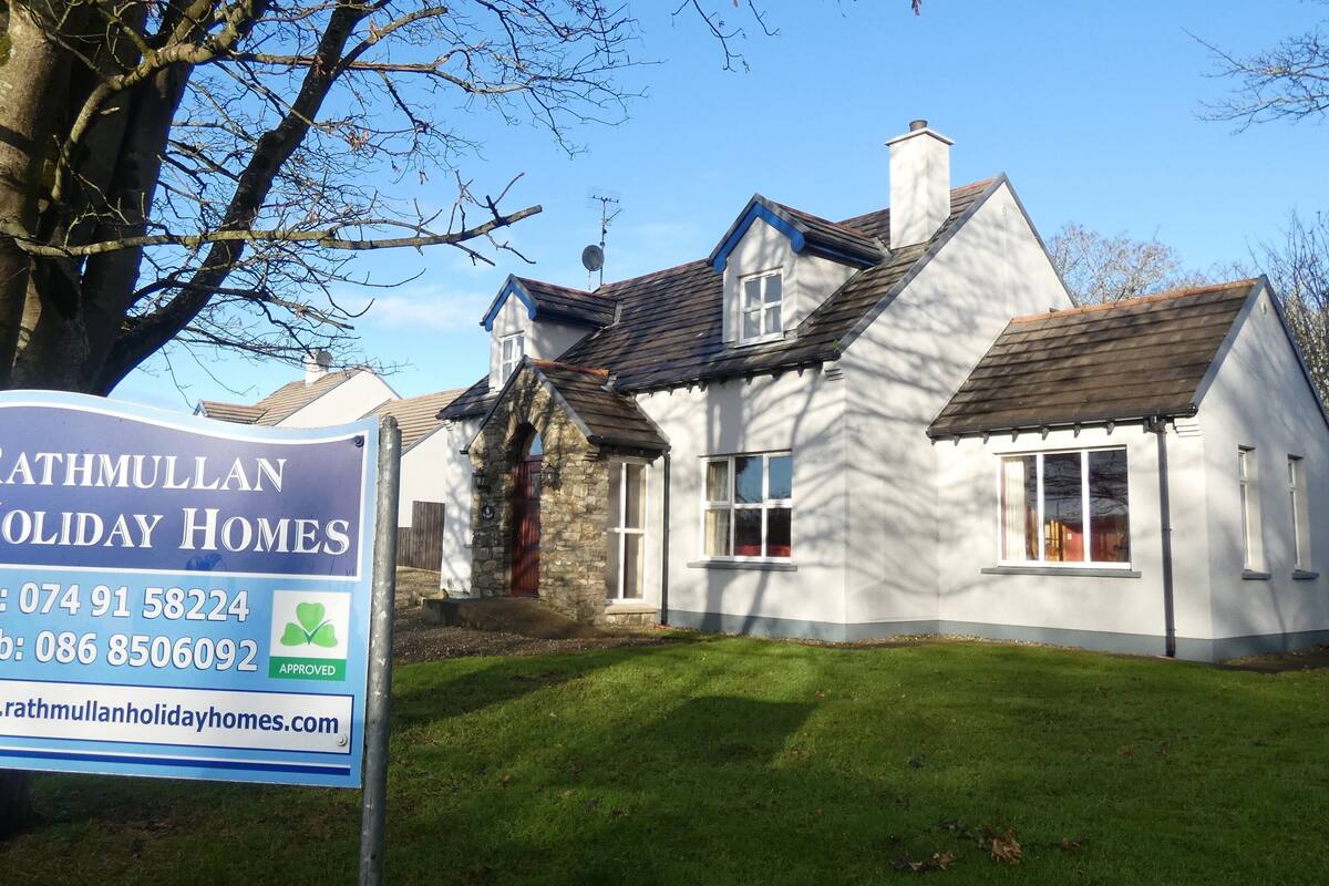 A two-story house with a stone foundation and a pitched roof.