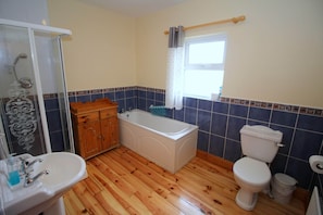 Un baño con ducha, lavabo, bañera, inodoro y suelo de madera.