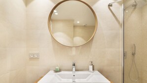 Ein modernes Badezimmer mit großem Spiegel, Waschbecken und Dusche.