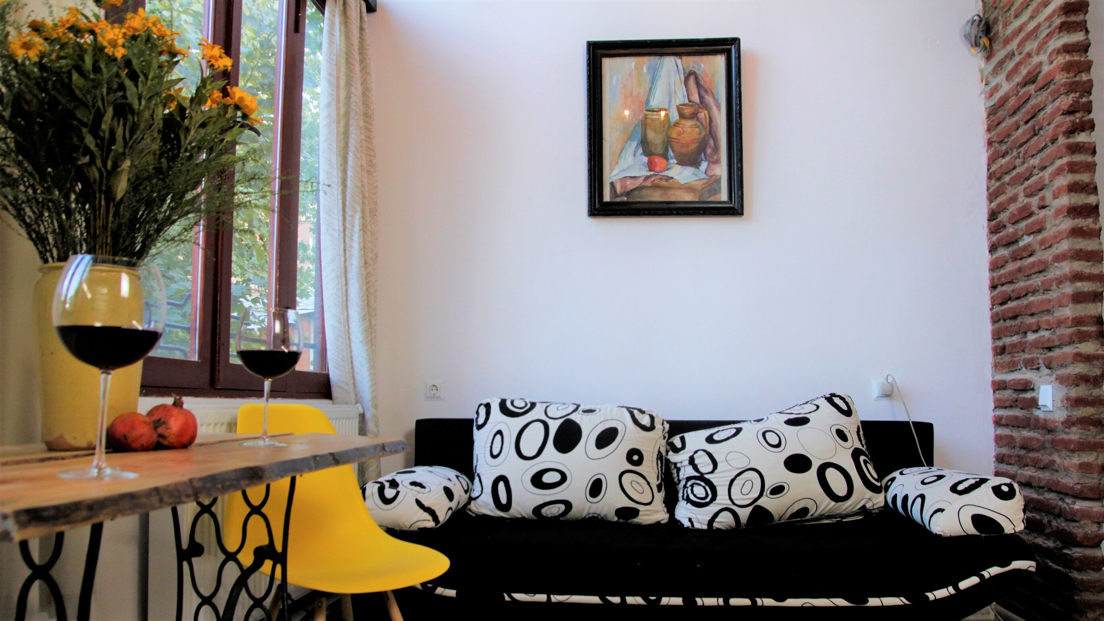 A living room with a sofa, a table with a vase of flowers, and a painting on the wall.