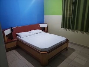 A single-bed room with a wooden frame, white bedding, a bedside table with a lamp, and a telephone. - Hotel Sany (São Paulo)