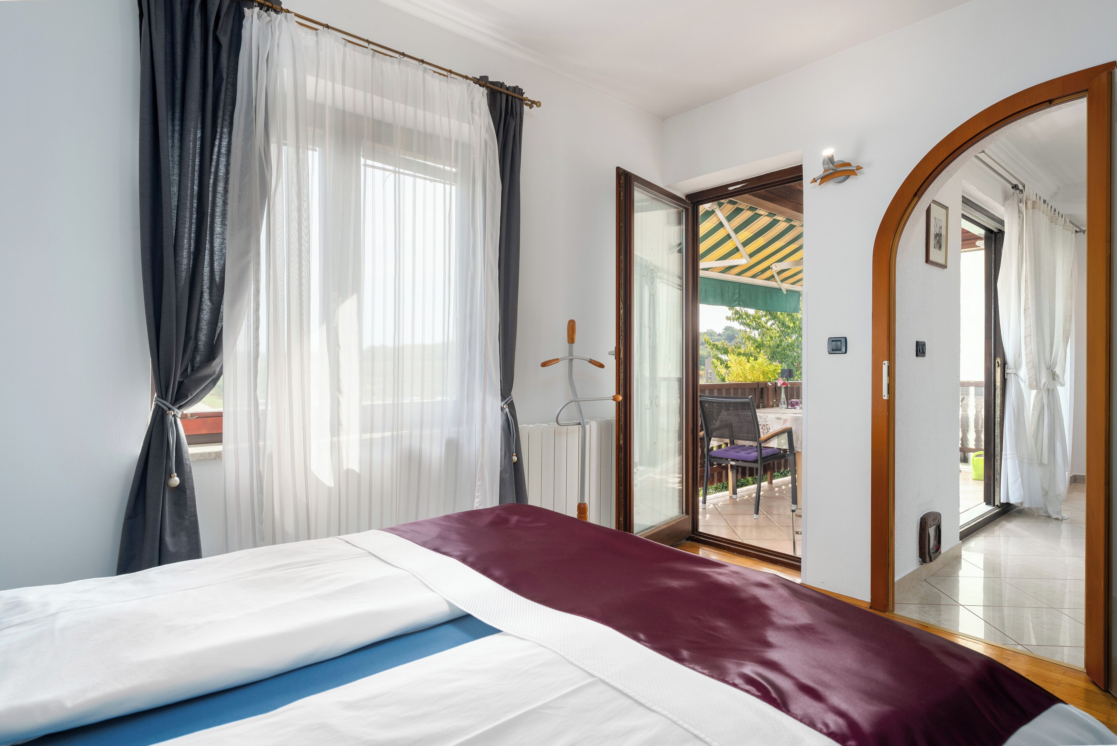 Ein Schlafzimmer mit einem Bett, einem großen Spiegel und einer Glastür, die zu einem Außenbereich führt.