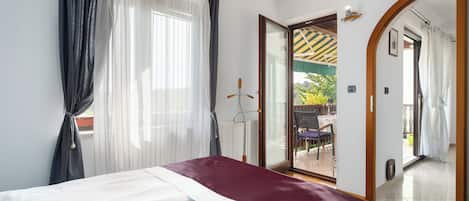 A bedroom with a bed, a large mirror, and a sliding glass door leading to an outdoor area.