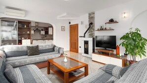 Uma sala de estar moderna com um conjunto de sofás, uma mesa de centro, uma televisão e uma lareira.