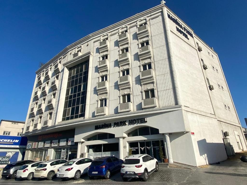 Un hôtel à plusieurs étages, doté d’une entrée imposante et de plusieurs voitures garées devant.