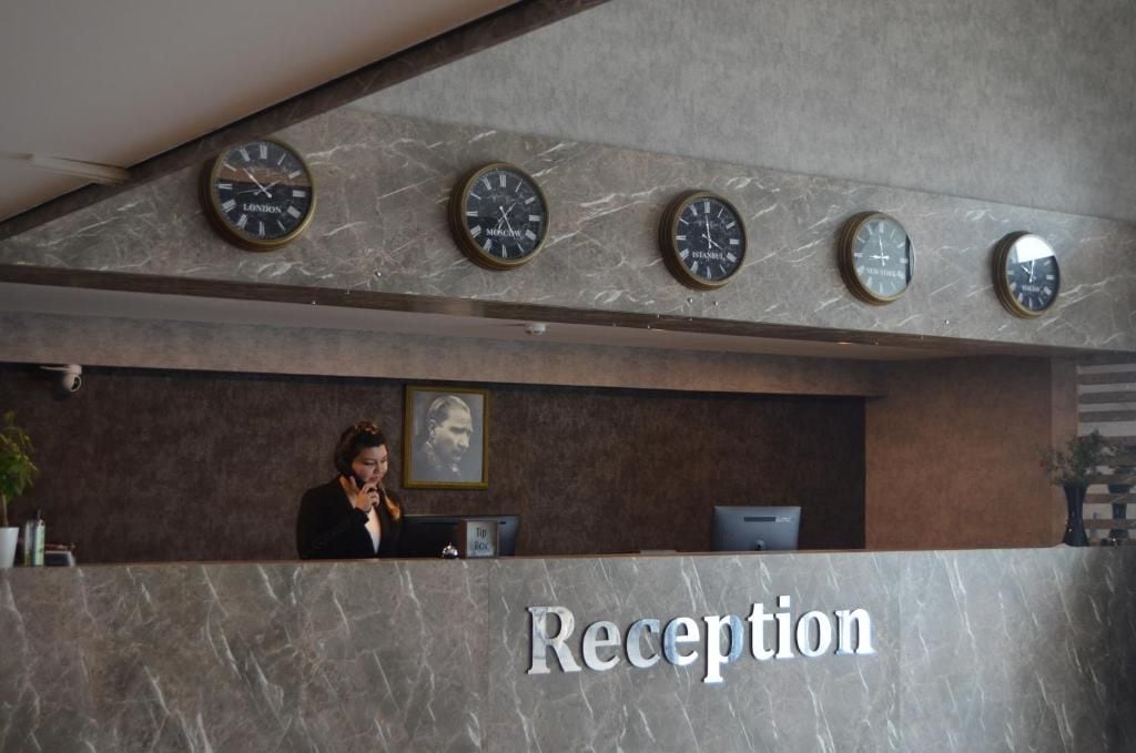 A reception area with a marble counter, multiple wall clocks, and a receptionist.