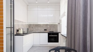 A modern kitchen with white cabinets, a built-in oven, and a coffee maker. - MinskLux Apartment on Nezavisimosti ave. 13 (Minsk)