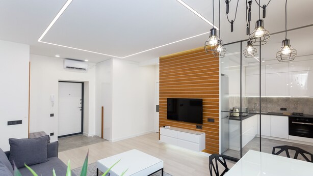 A modern living room with a sofa, coffee table, and TV. There is a kitchen area with a TV and cabinets. - MinskLux Apartment on Nezavisimosti ave. 13 (Minsk)