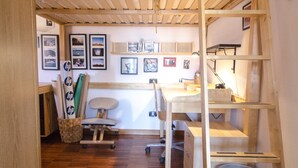 Ein Zimmer mit Etagenbett, Holzschreibtisch, Stuhl und Regalen.