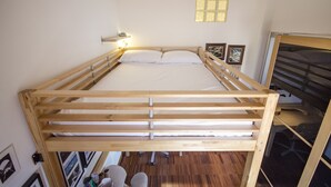 Ein Stockbett mit Holzrahmen, Kopfteil und Nachttisch mit Lampe.