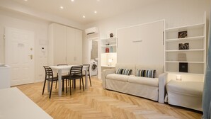 A modern apartment with a dining area, a sofa, and a built-in bookshelf. - Calzolerie studio (Bologna)