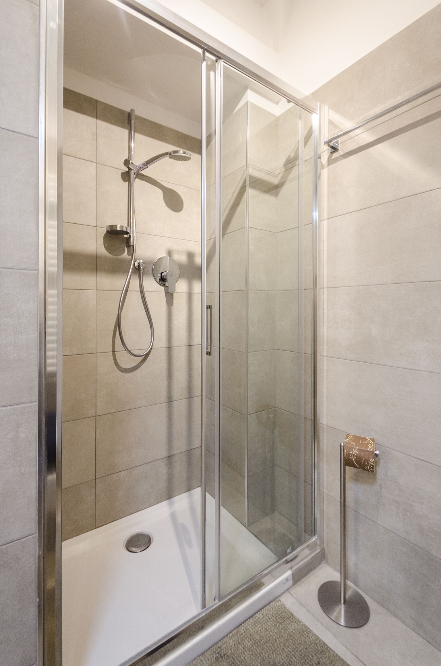 Une cabine de douche fermée par des parois en verre, dotée d’un pommeau de douche à main et d’un robinet mural.