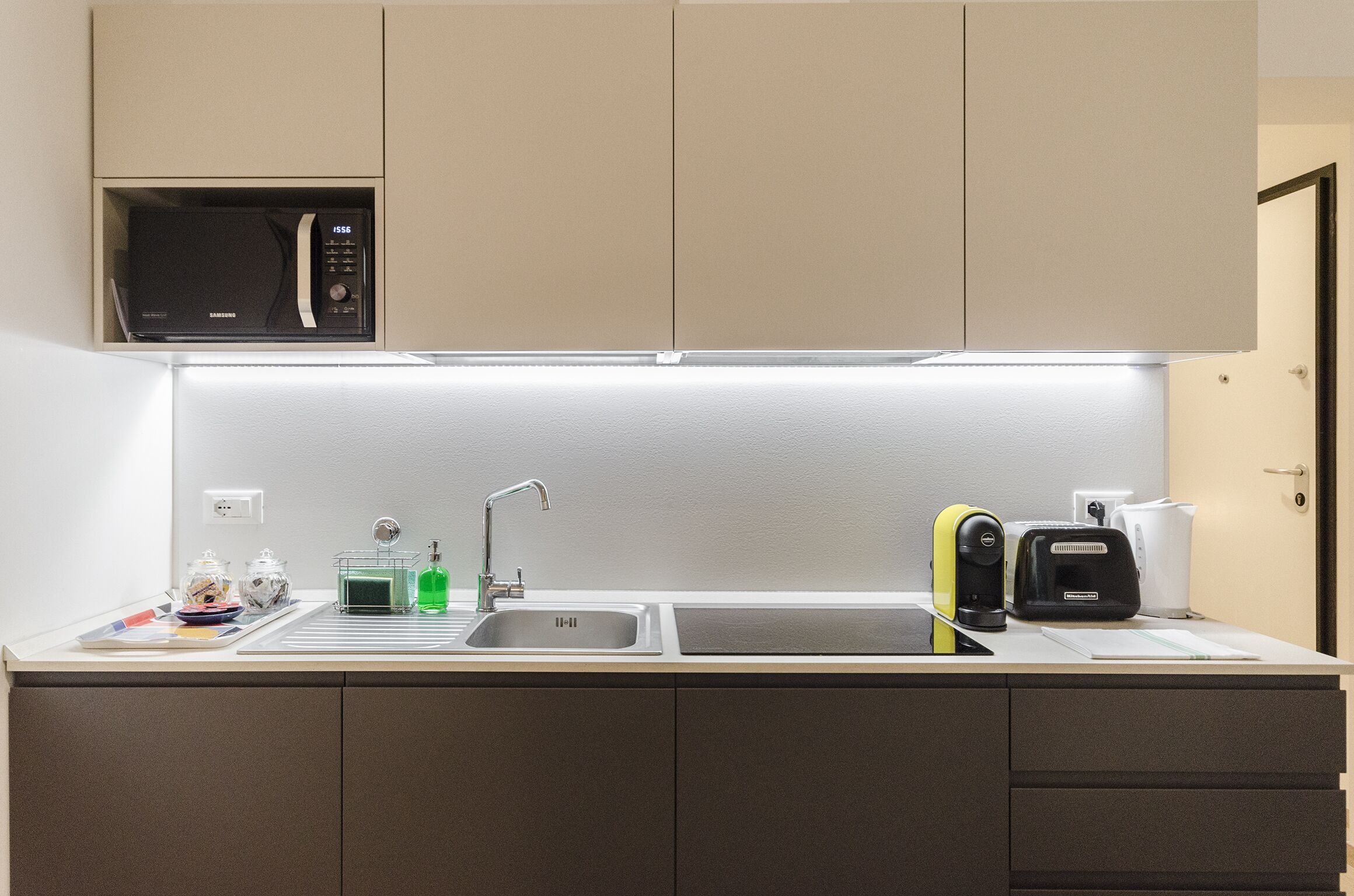 Una cocina moderna con microondas, pileta y cafetera.