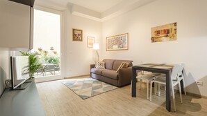 Una sala de estar moderna con un sofá, una mesa de comedor con sillas, un televisor y obras de arte en las paredes.