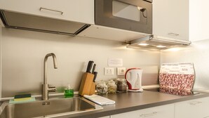 A modern kitchen with a stainless steel sink, a kettle, and various kitchen utensils. - Appartamento del Nettuno (Bologna)