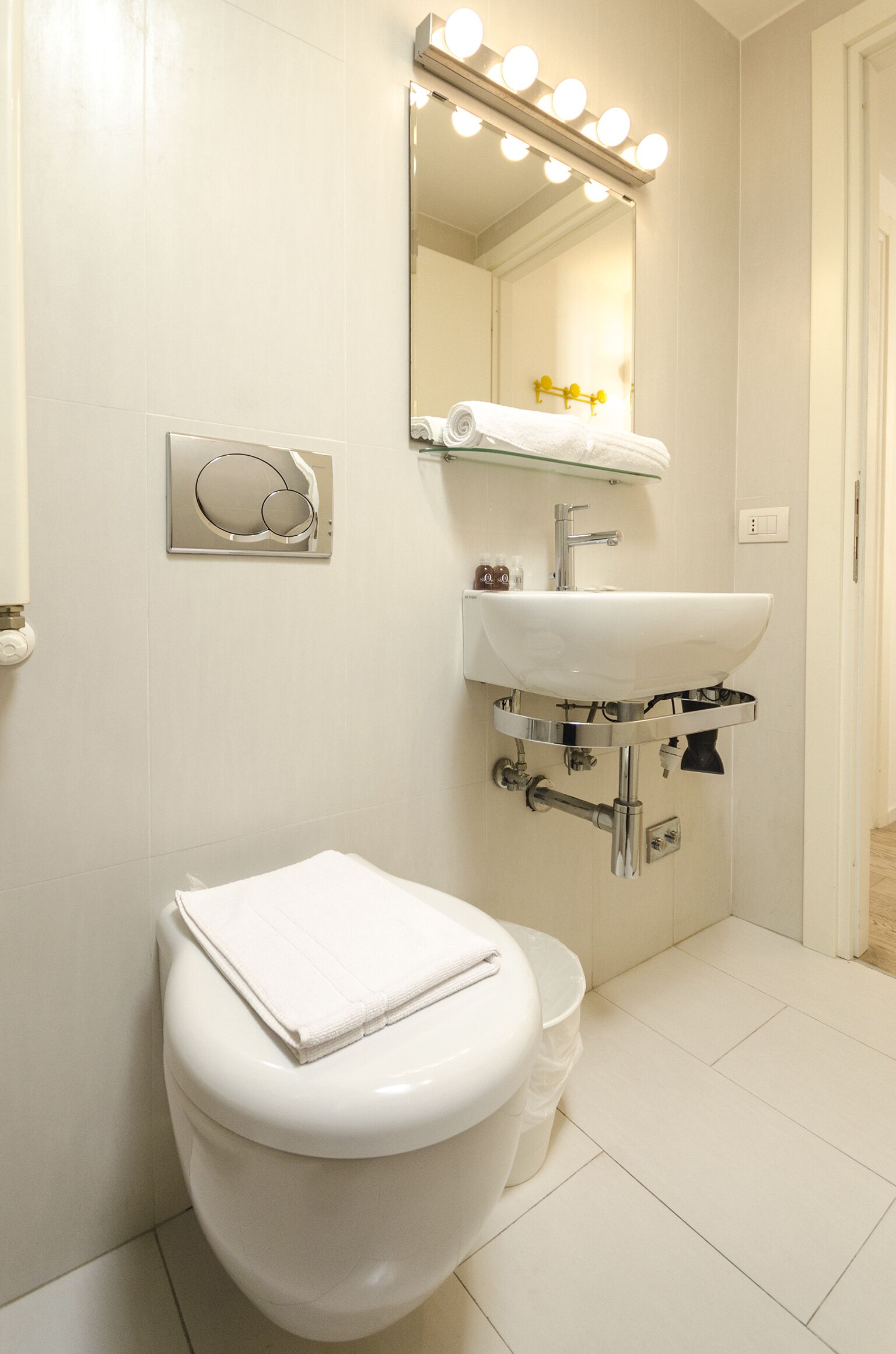 A bathroom with a white toilet, a sink with a mirror above it, and a towel rack.