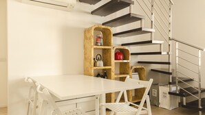 A modern kitchen with white cabinetry, a built-in stove, and a wooden shelf unit with kitchen items. - Appartamento del Nettuno (Bologna)