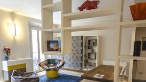 A modern interior with a wooden floor, a blue rug, a bean bag, a dining table with chairs, and a white reception desk.