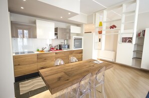 Eine moderne Küche mit Holzschränken, einem Holztisch und klaren Stühlen.