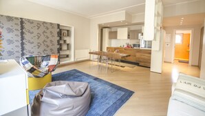 A modern living room with a sofa, a coffee table, and a dining area with chairs and a table.
