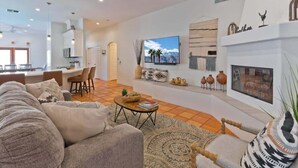 A modern living room with a sofa, coffee table, and a fireplace. - Hacienda Getaway Pool, Hot Tub, & Steps to trails. (La Quinta)